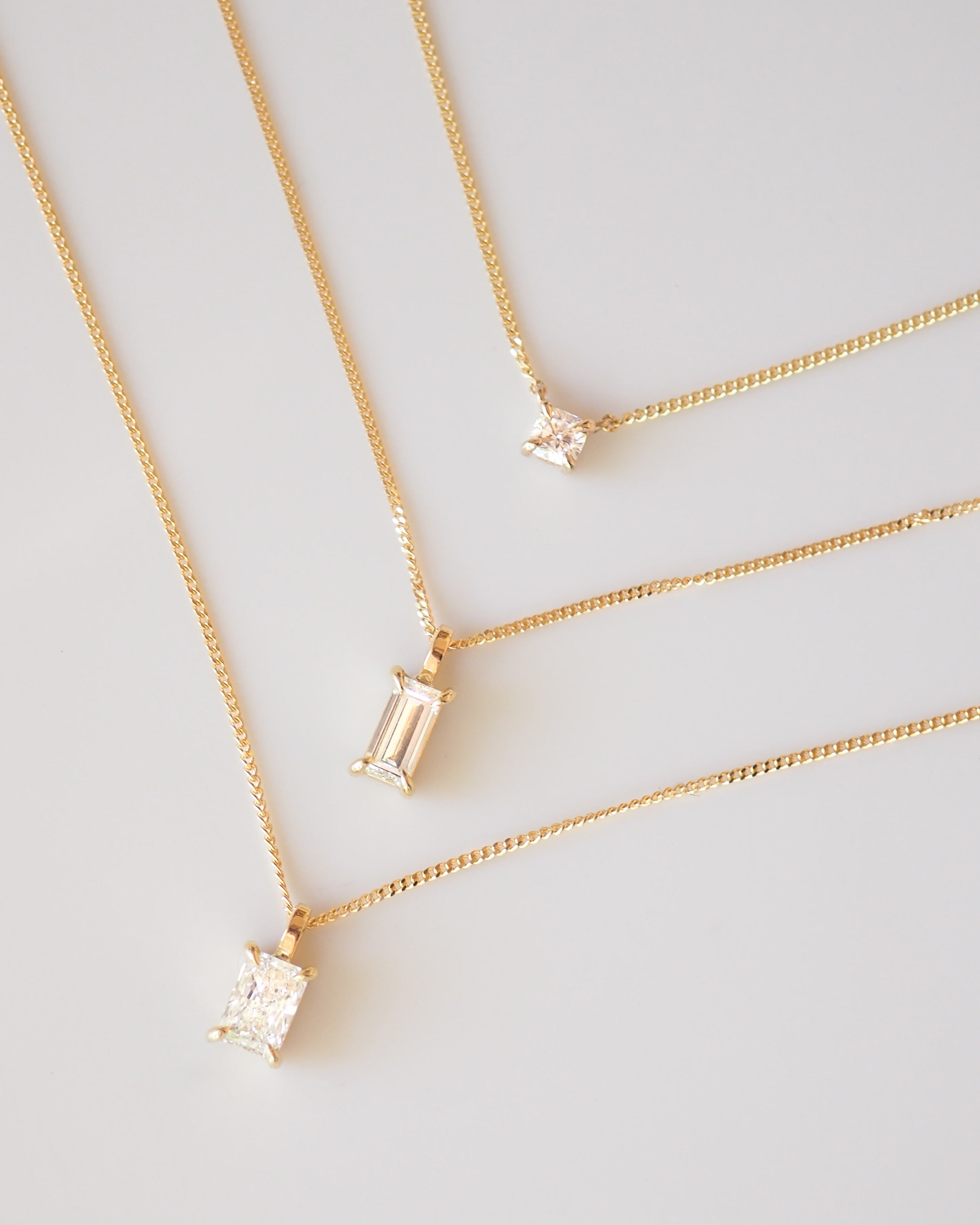 Gold necklaces featuring lab-grown diamond pendants by Kate & Kole, displayed against a soft neutral background