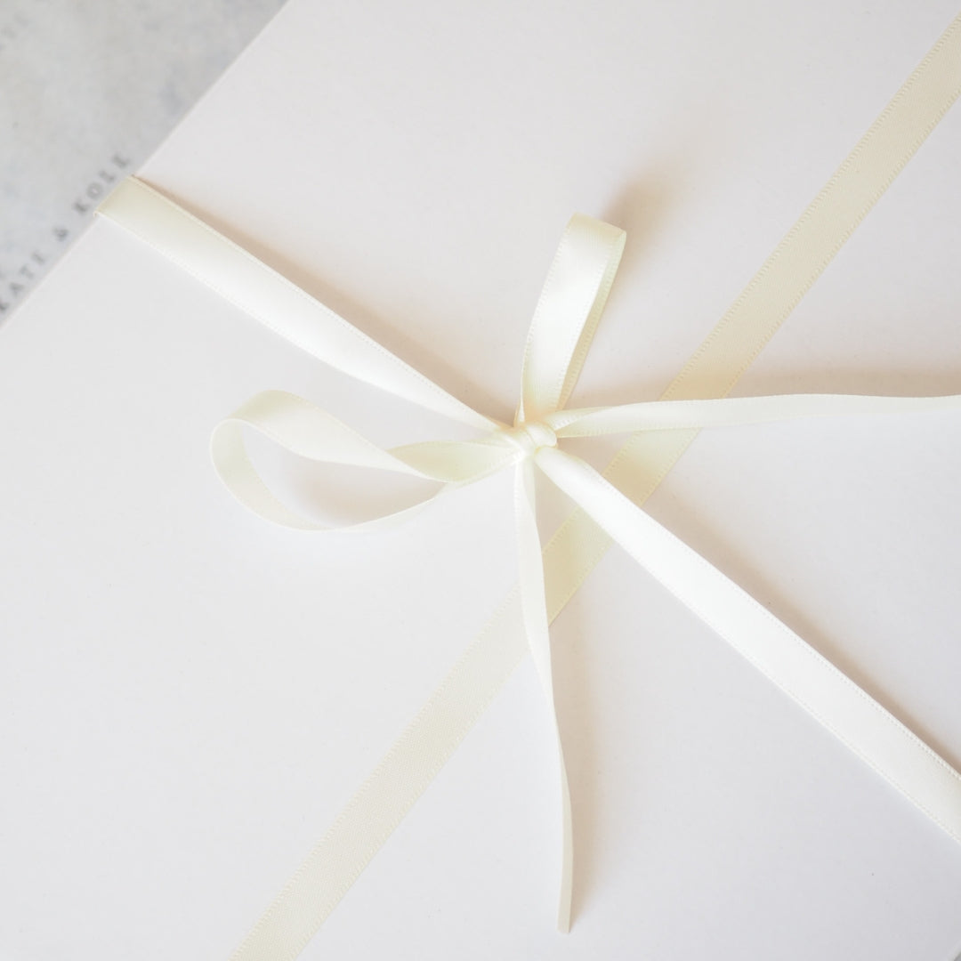 White gift box with a gold ribbon on a white background