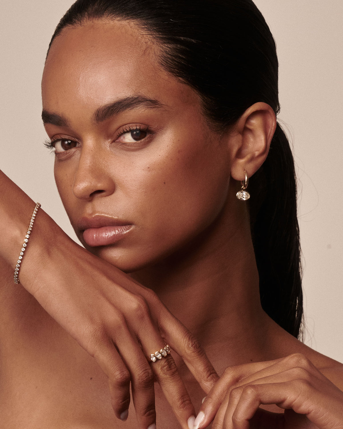 Model wearing Kate & Kole's Bezel Diamond Drop Earring, Bezel Diamond Bracelet and Lola Diamond Bezel Band in yellow gold, featuring lab-grown diamonds.