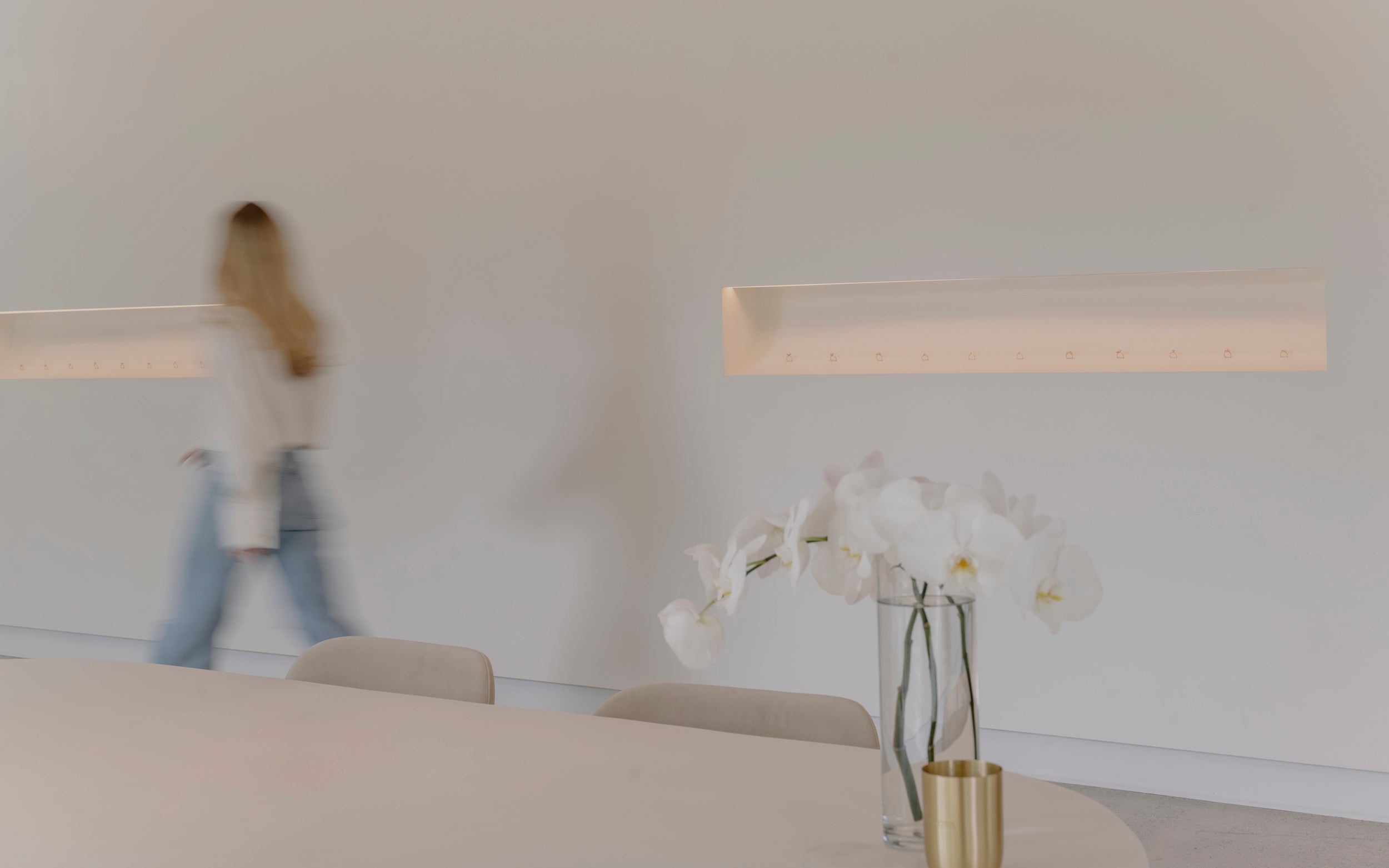 Modern interior with a vase of white flowers on a table, blurred figure in the background