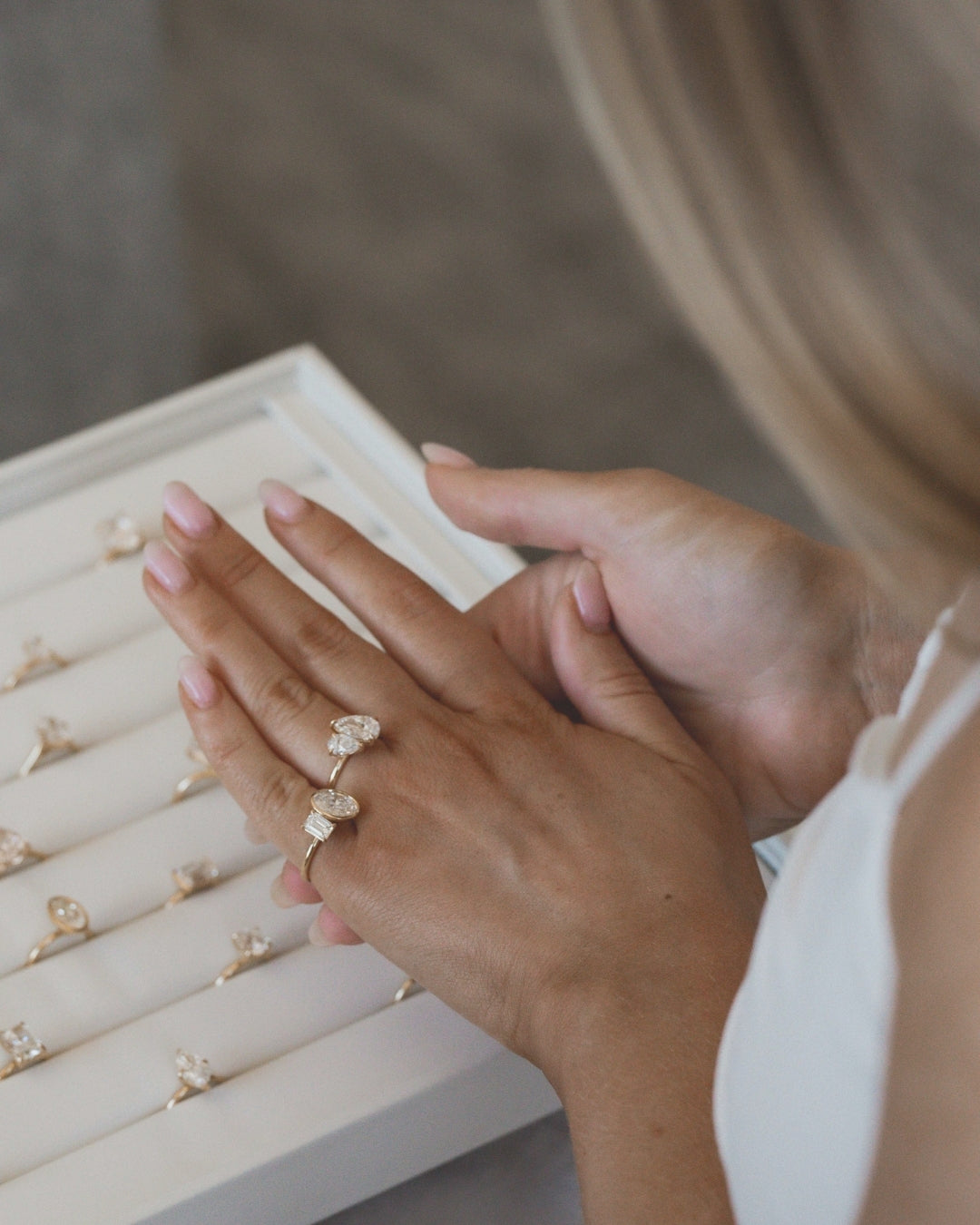 Hand wearing a gold ring with a diamond, with a jewelry box in the background