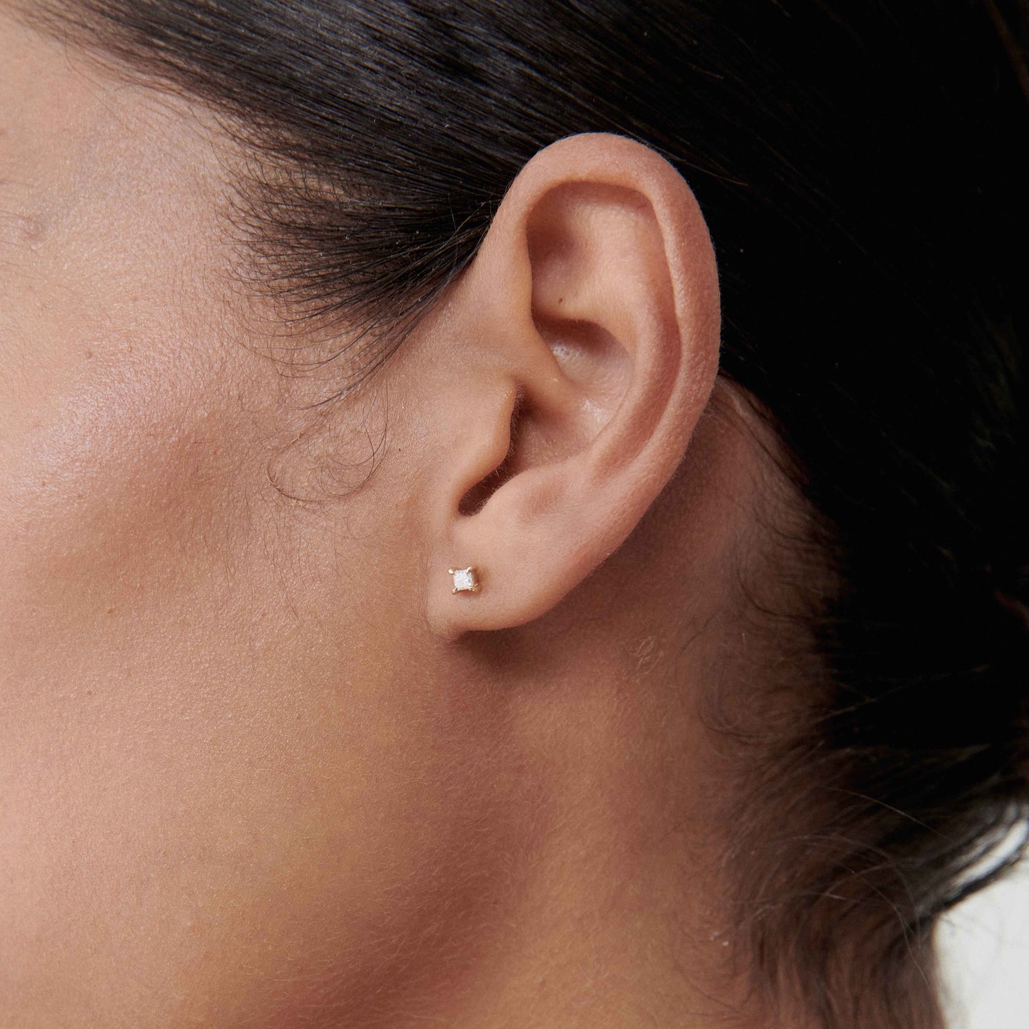 Close-up of a woman's ear wearing a small, elegant pearl stud earring. Perfect for minimalistic, luxury jewellery lovers.