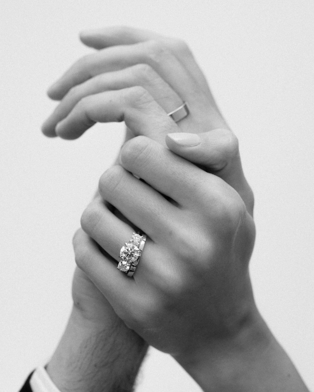Couple holding hands with Kate & Kole engagement ring and wedding bands 