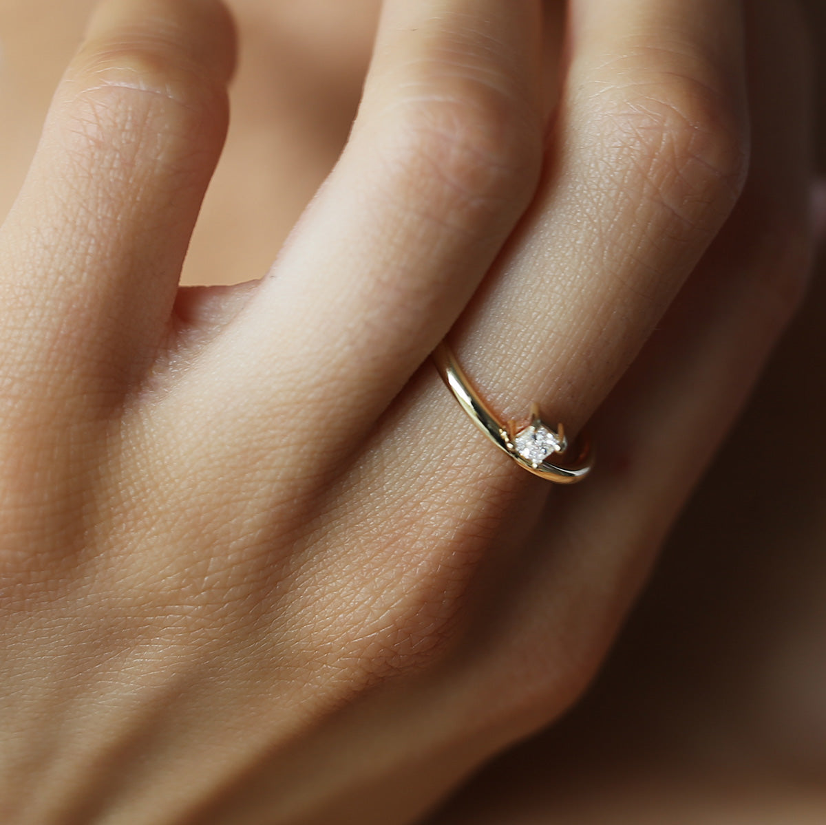 Close-up of a hand wearing a gold engagement ring with a square-cut diamond. Luxurious jewellery, elegant and sophisticated design.