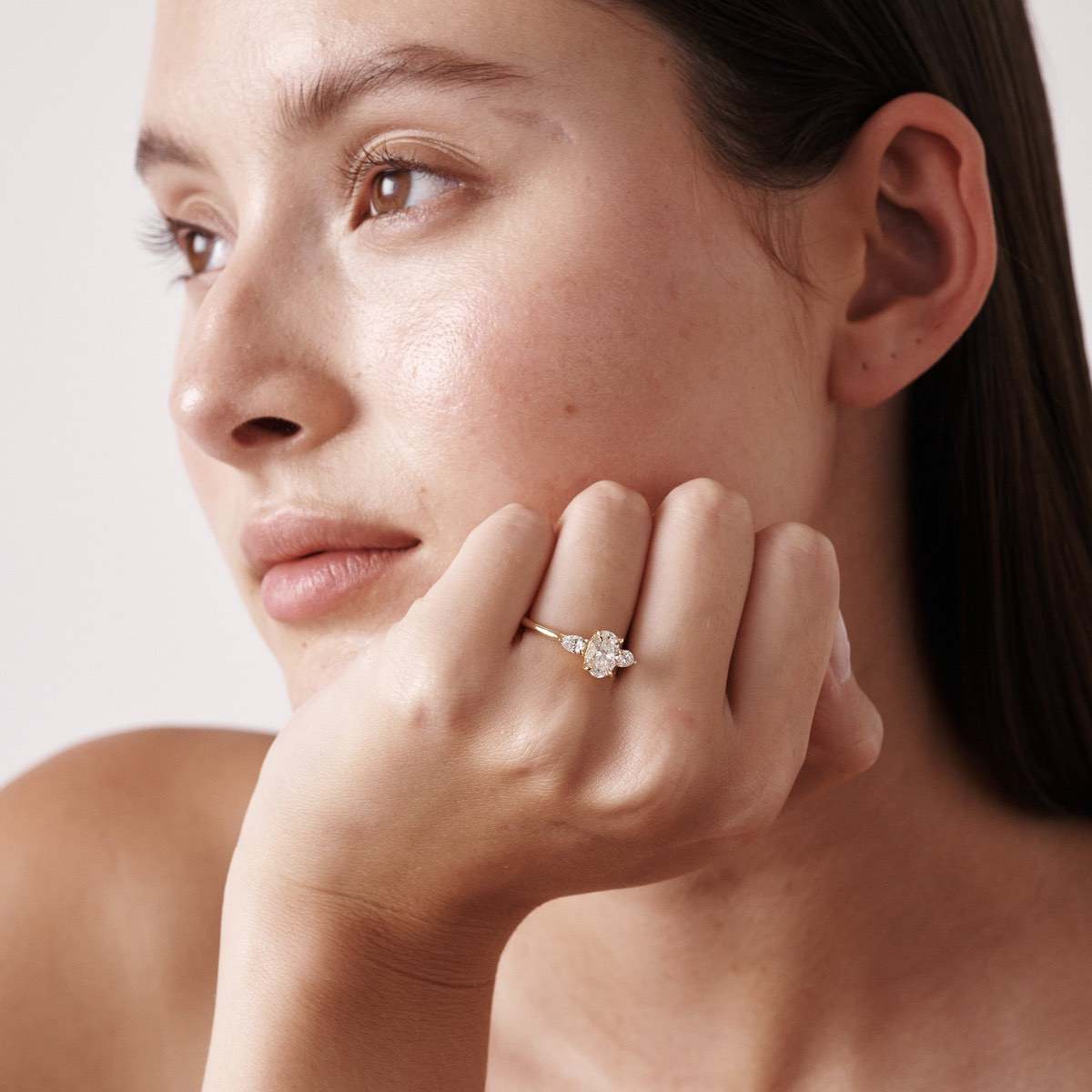 Model wearing our Ania lab grown diamond ring. Model is opening our white leather ring box feauturing Ania.Our Ania ring showcases an oval centre stone shining between two smaller-sized pear shoulder stones. The ring pictured features a 1.00ct oval lab grown diamond and set in 18ct yellow gold.