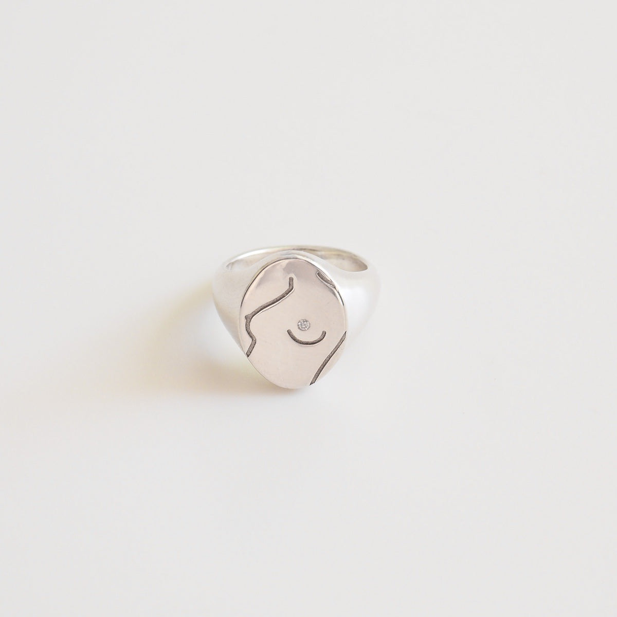 Silver ring with a feminine design on a light gray background
