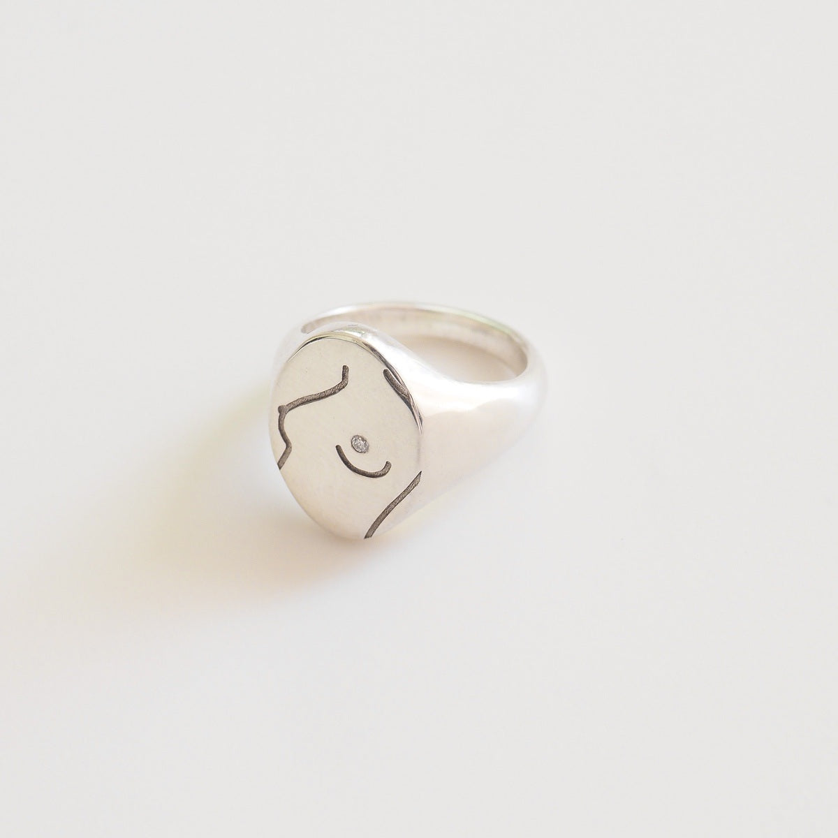 Silver ring with a feminine design on a light gray background