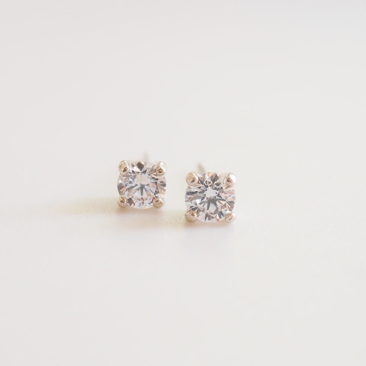 Pair of diamond stud earrings on a light gray background