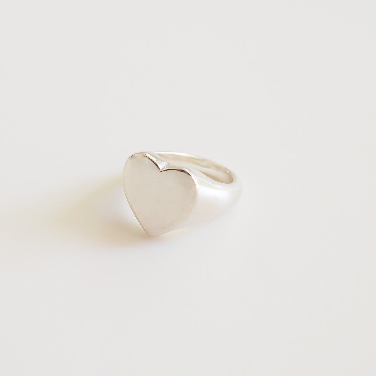 Heart-shaped silver ring on a light gray background