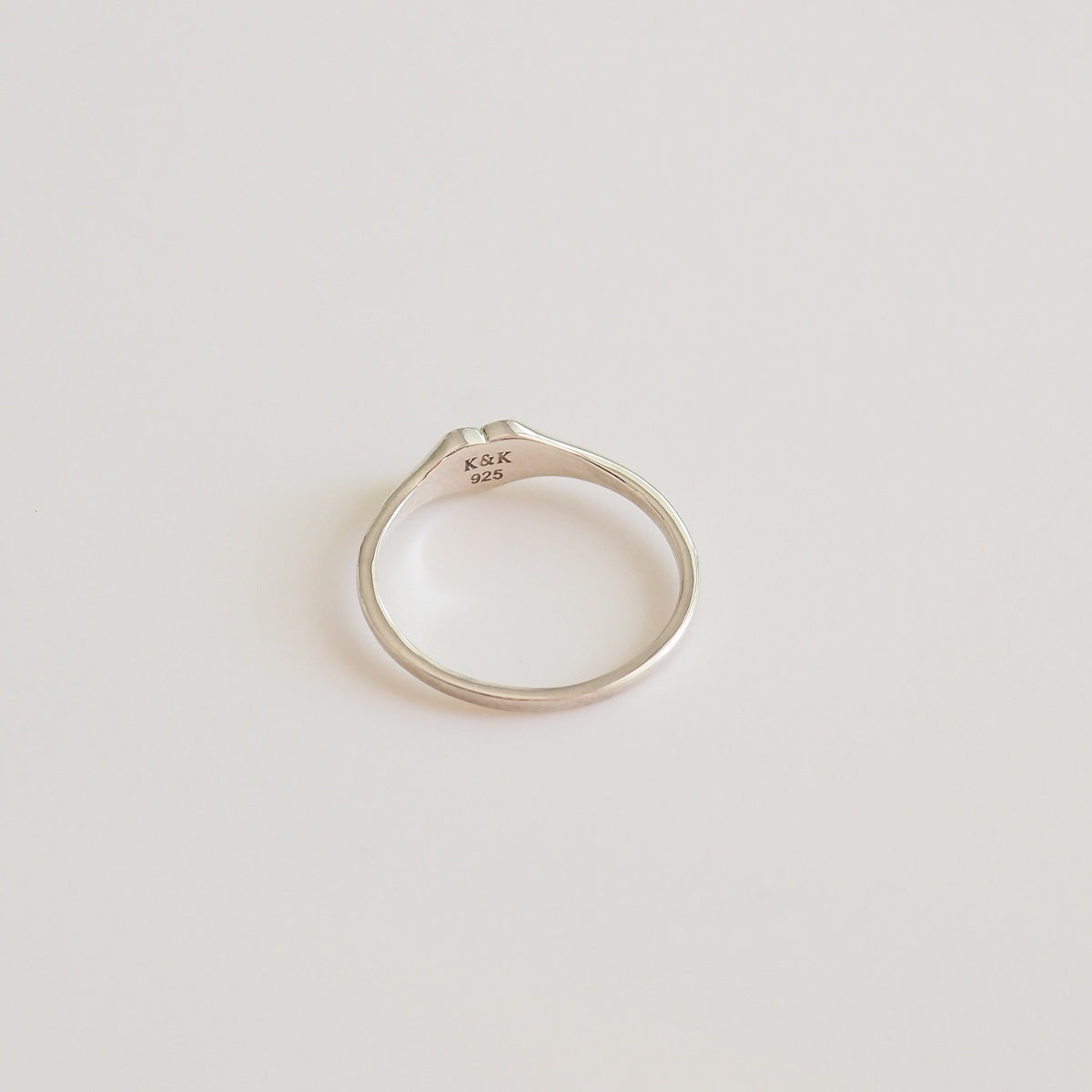 Silver ring with engraved text on a light gray background