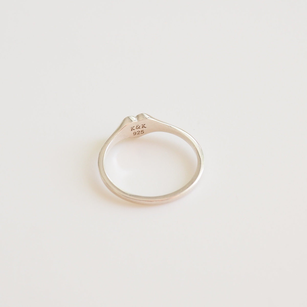 Silver ring with 'K&K' engraving on a light gray background