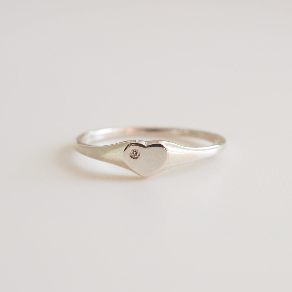 Silver ring with a heart-shaped design on a light gray background