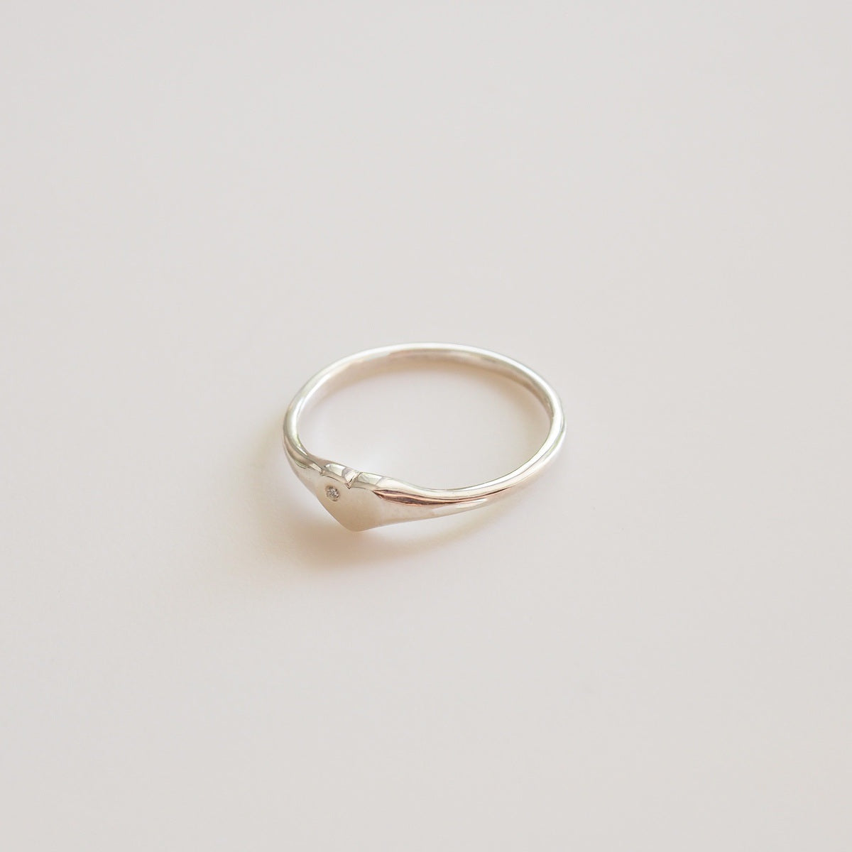Silver ring with a small diamond on a light gray background