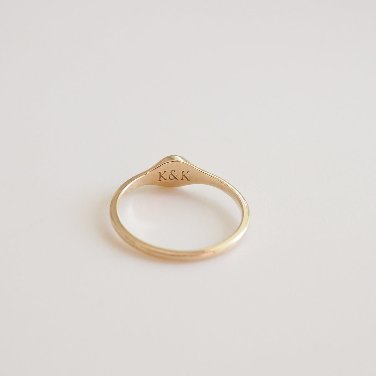 Gold ring with 'K&K' engraving on a light gray background