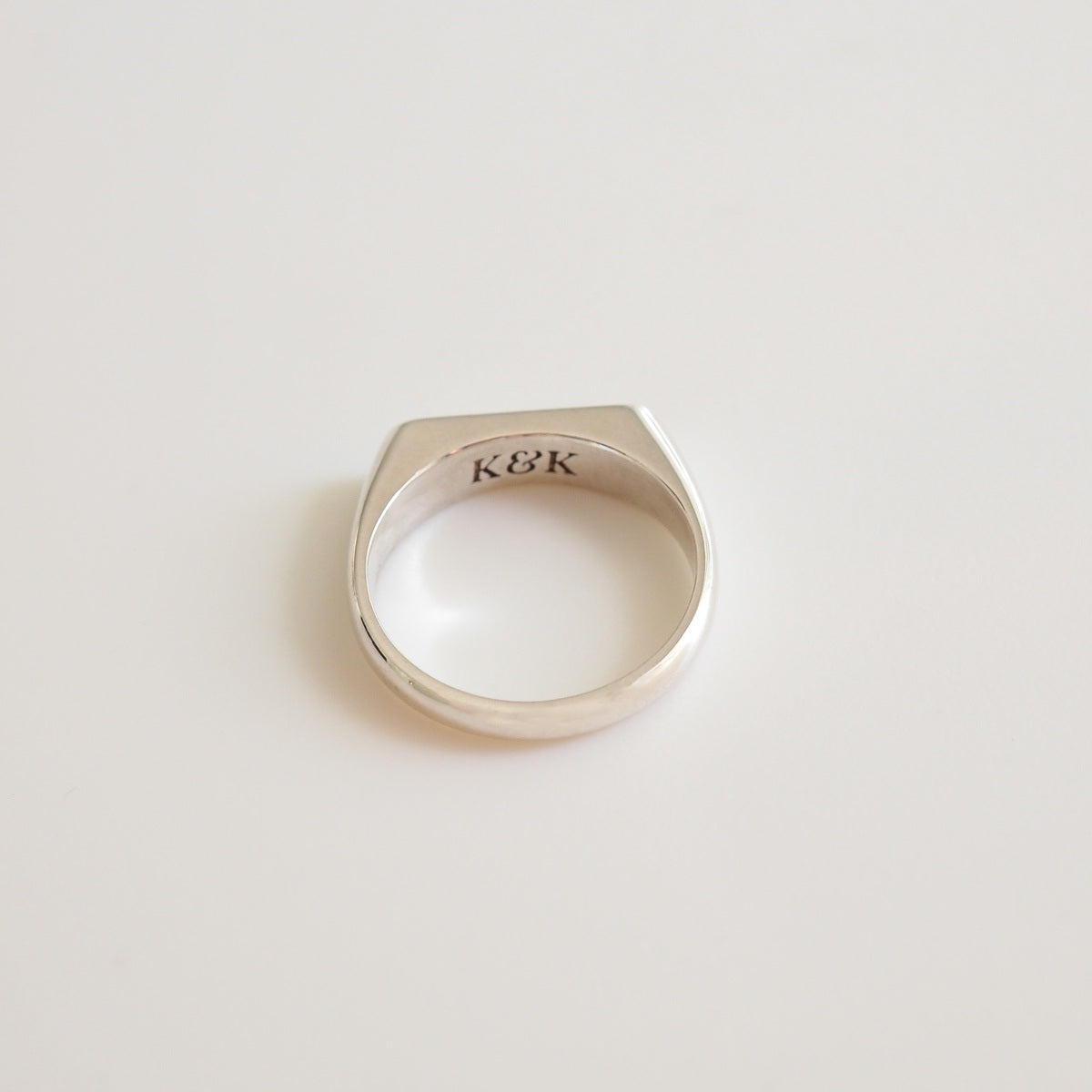 A flaylay of a narrow silver signet ring on a white background