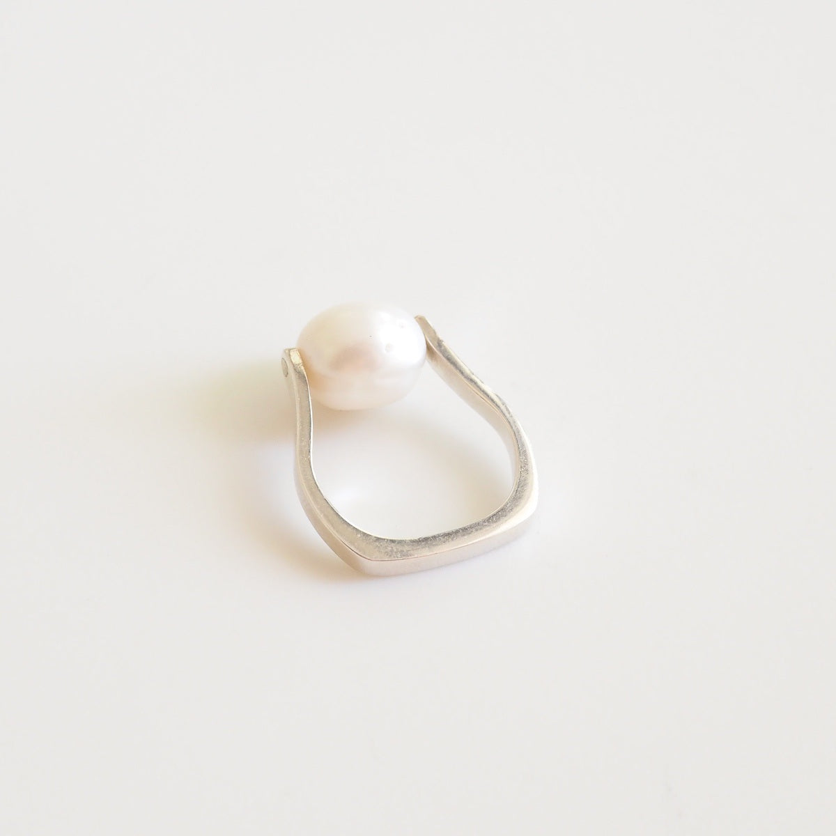 Silver ring with a pearl on a light gray background