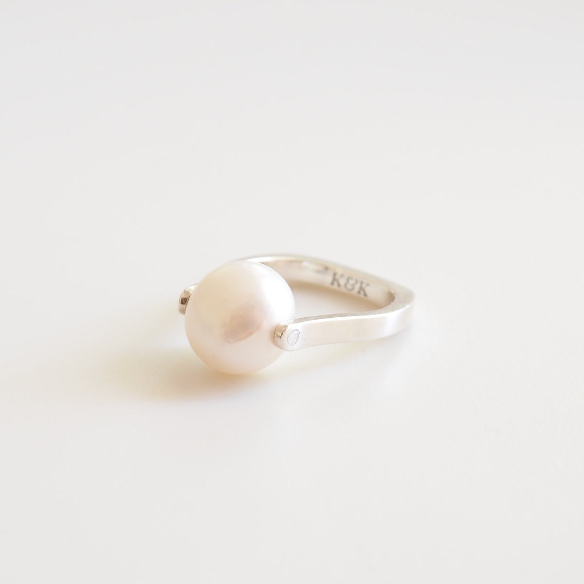 Silver ring with a pearl on a light gray background
