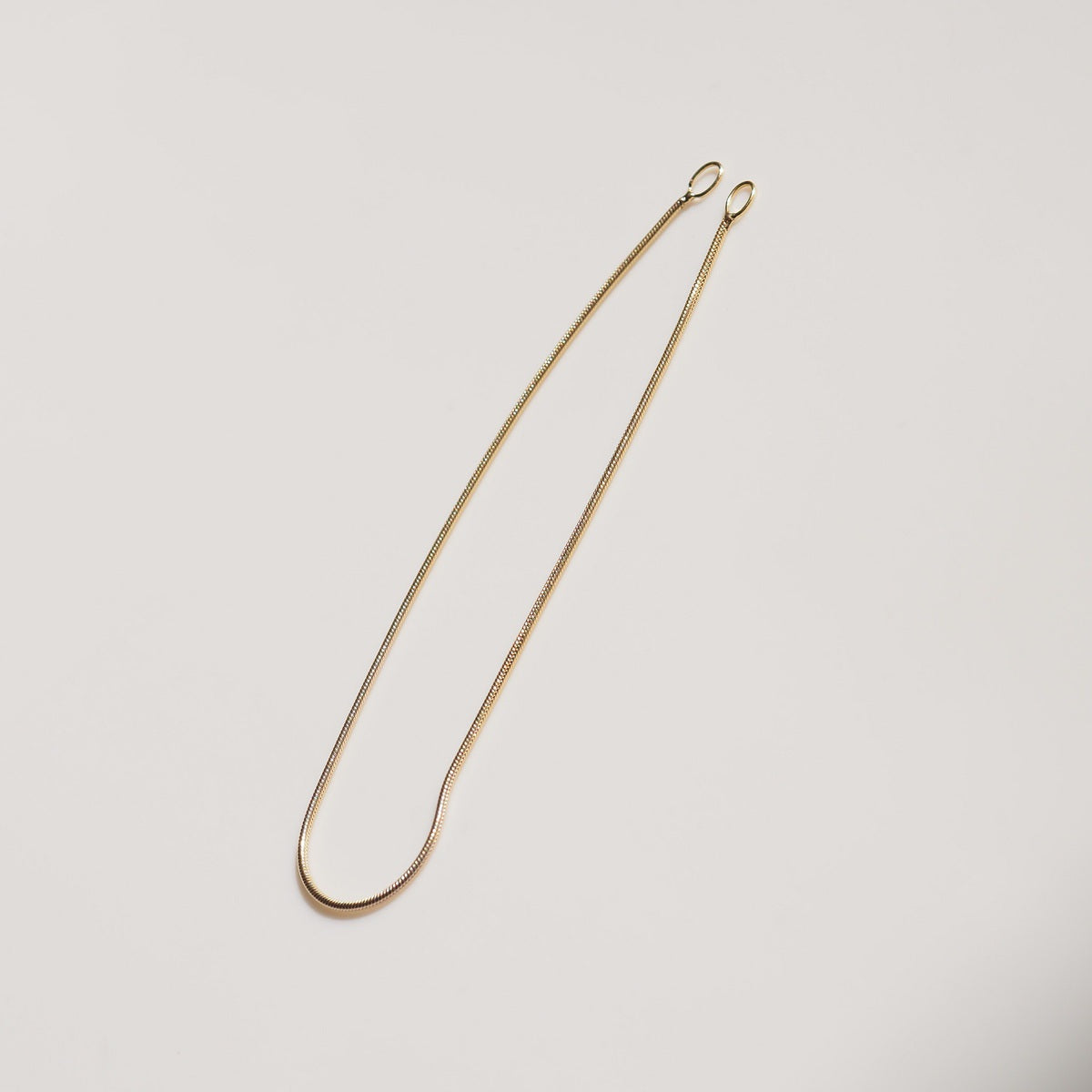 a flat lay of our Snake Chain Drops styled on a cream background