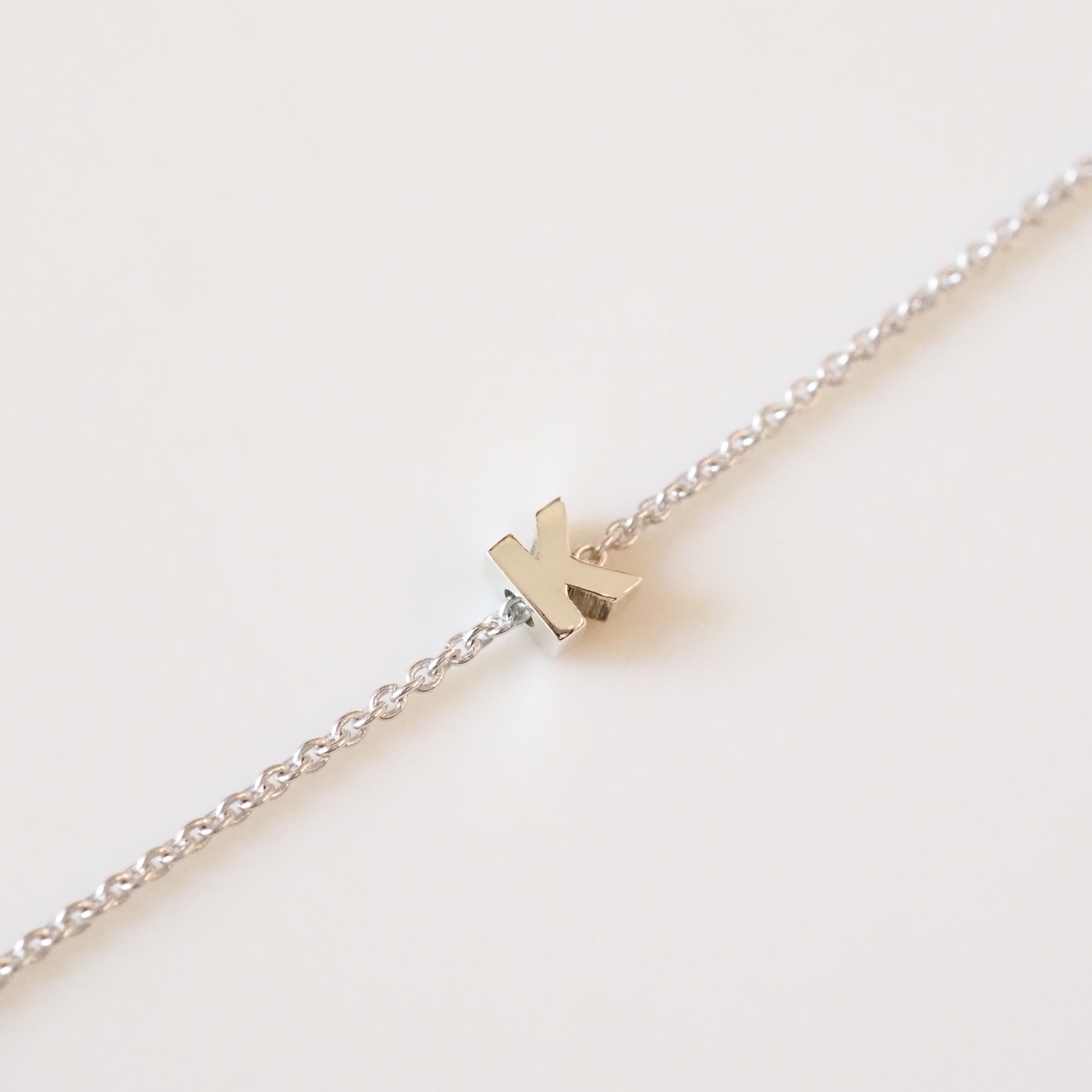 Silver bracelet with a small pendant on a light beige background