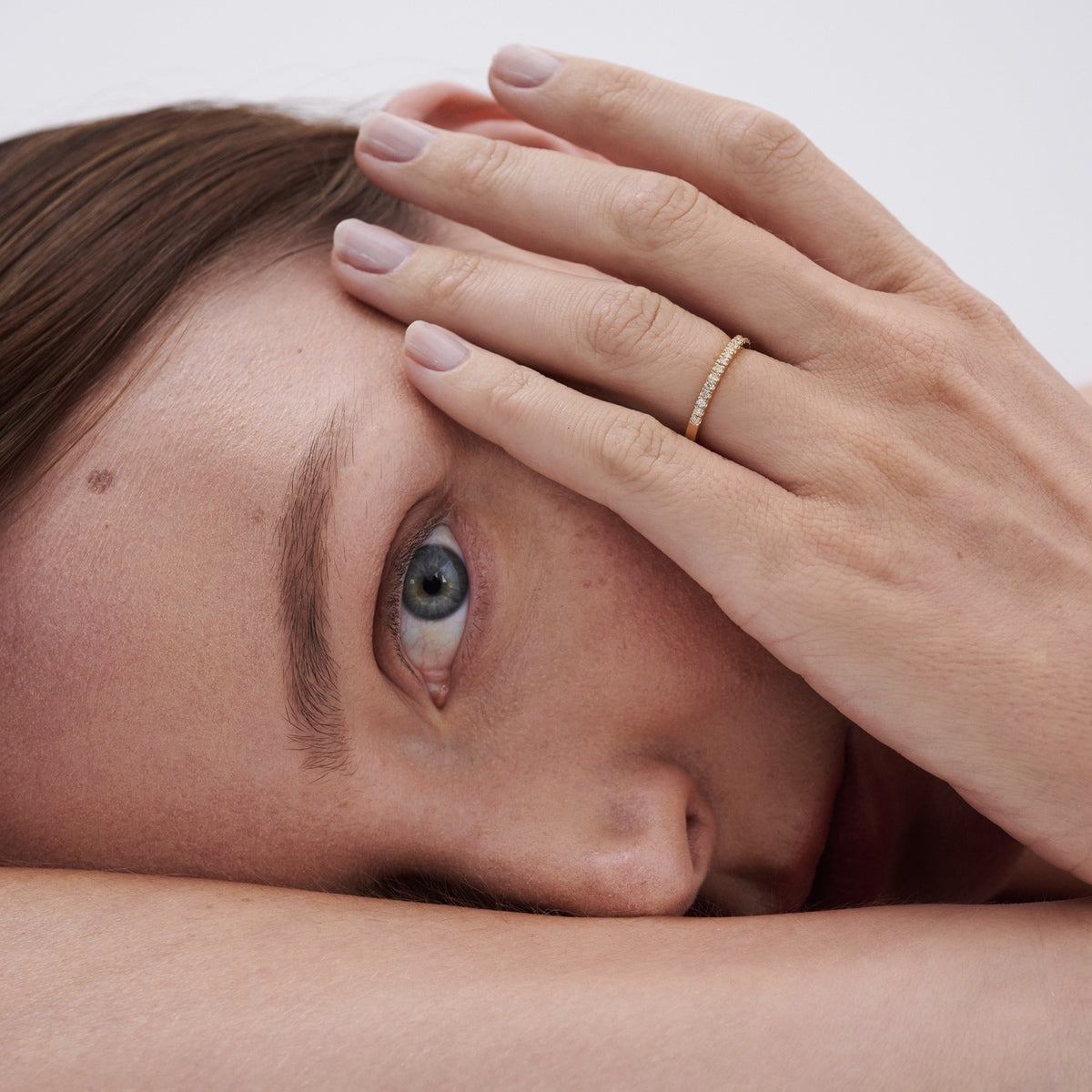 Models headshot wearing Amaré 18ct yellow gold 1.4mm diamond set band on her wedding finger 