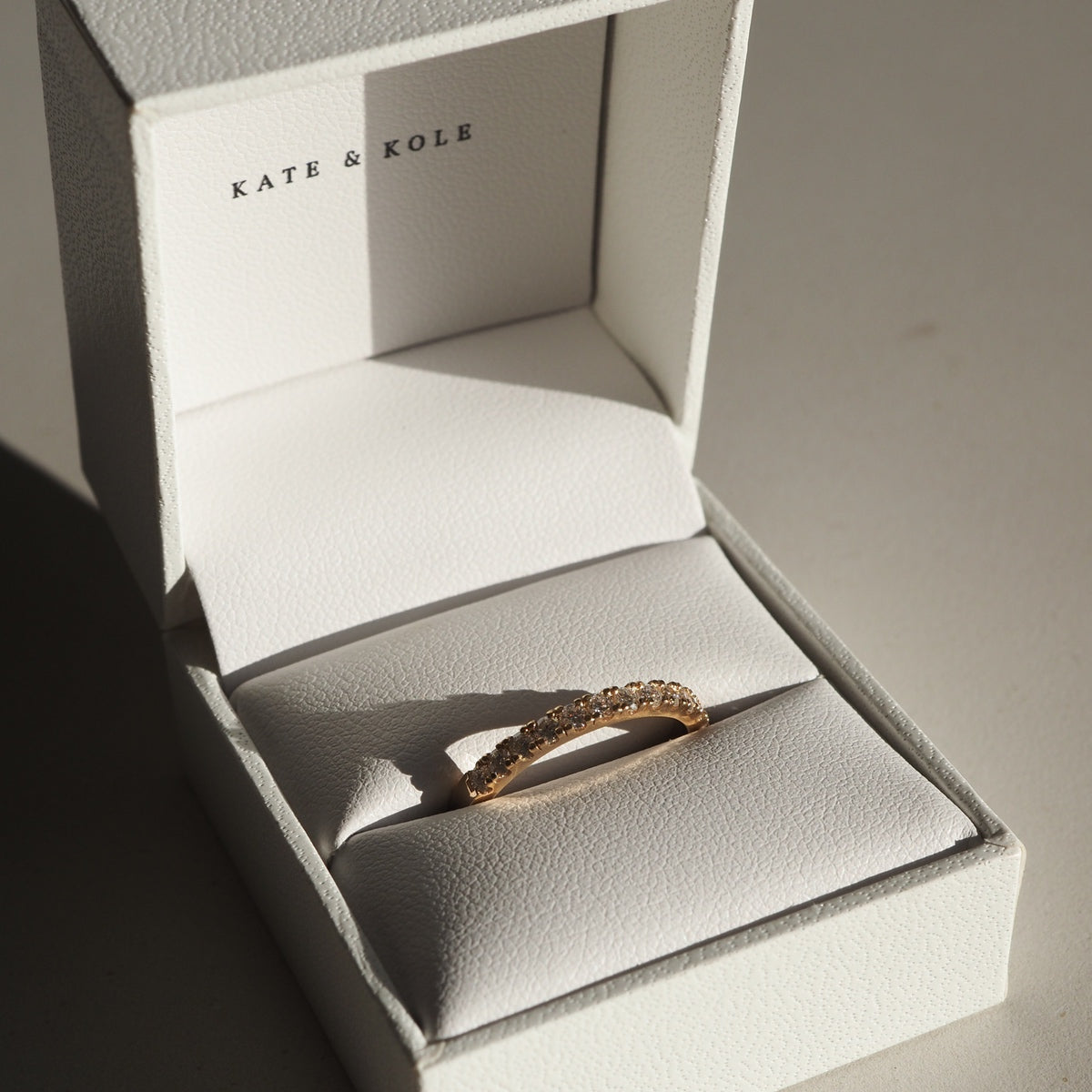 Amaré 1.4mm diamond wedding band set in 18ct yellow gold sitting in Kate and Kole white leather ring box 