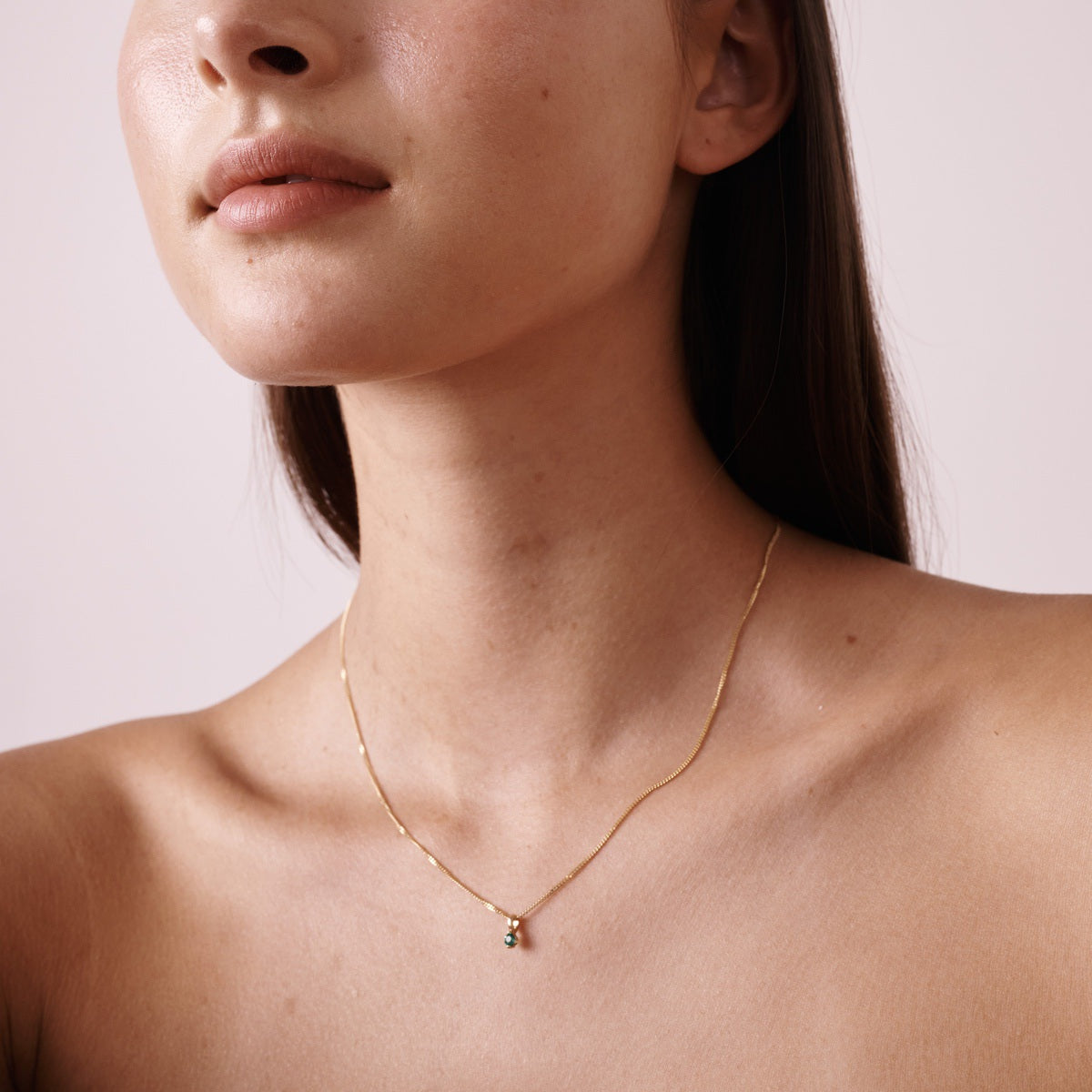 Model wears our 9ct yellow gold birthstone necklace with an emerald stone hung upon a 45cm diamond curb chain