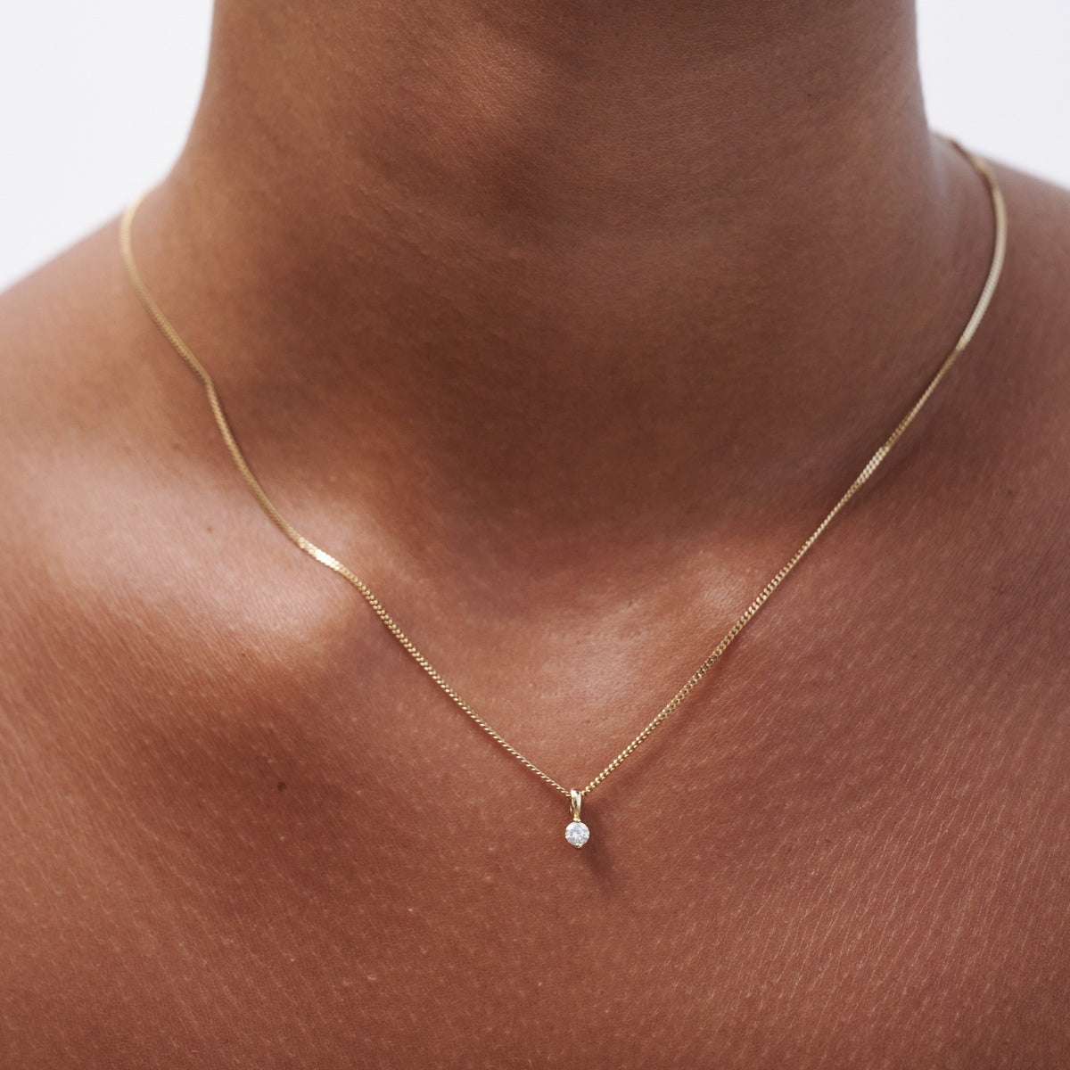 Model wears our 9ct yellow gold lab grown diamond birthstone necklace hung upon a 45cm diamond curb chain