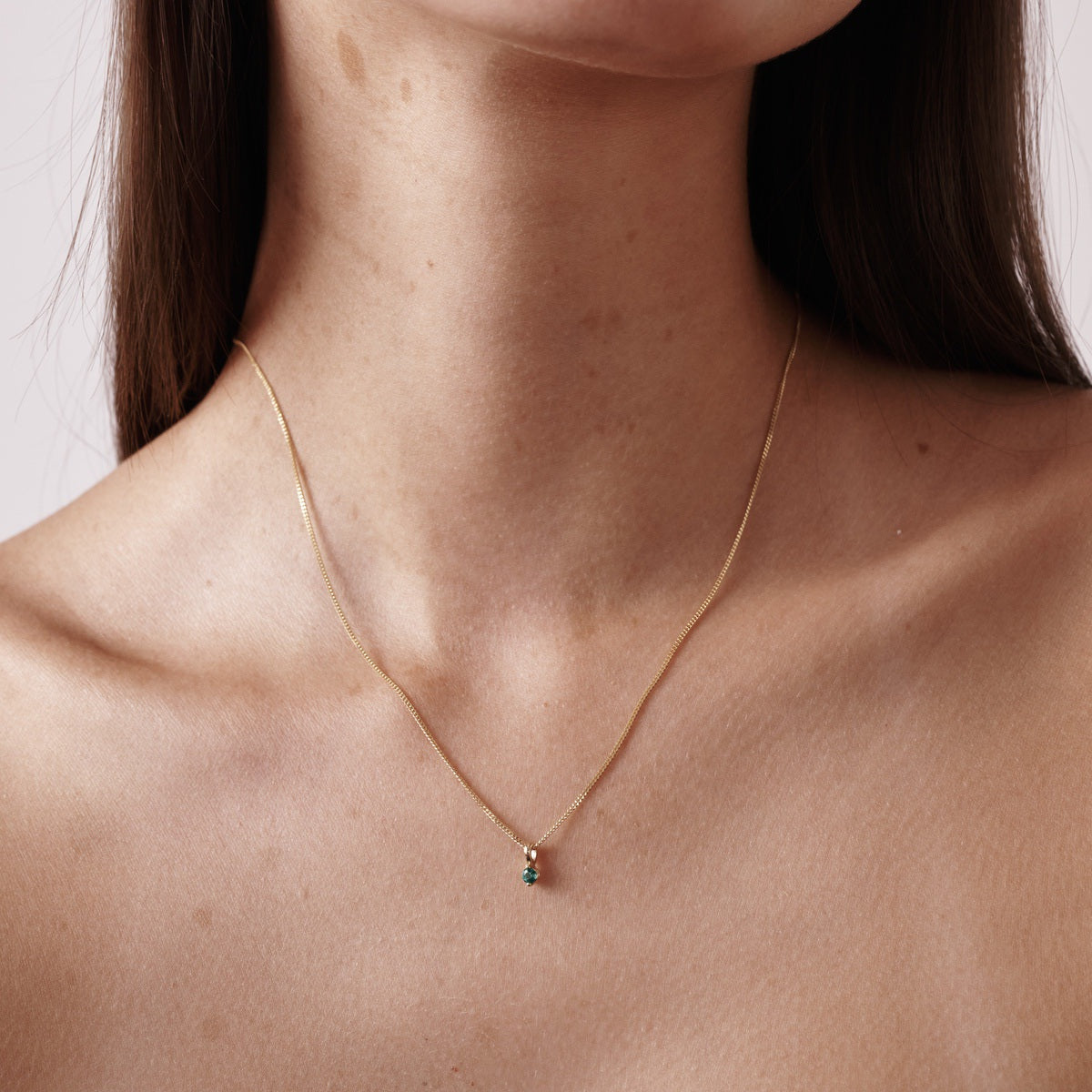 Model wears our 9ct yellow gold birthstone necklace with an emerald stone hung upon a 45cm diamond curb chain