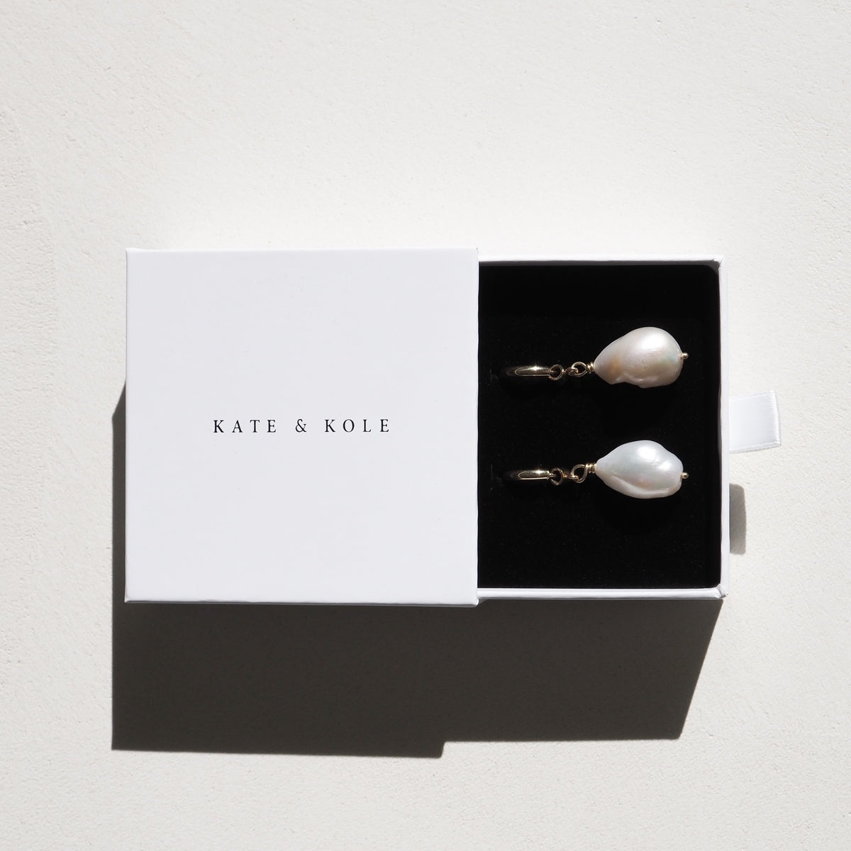 A Kate & Kole jewellery box reveals a complimentary pair of freshwater pearl earrings in 9ct yellow gold, drenched in sun