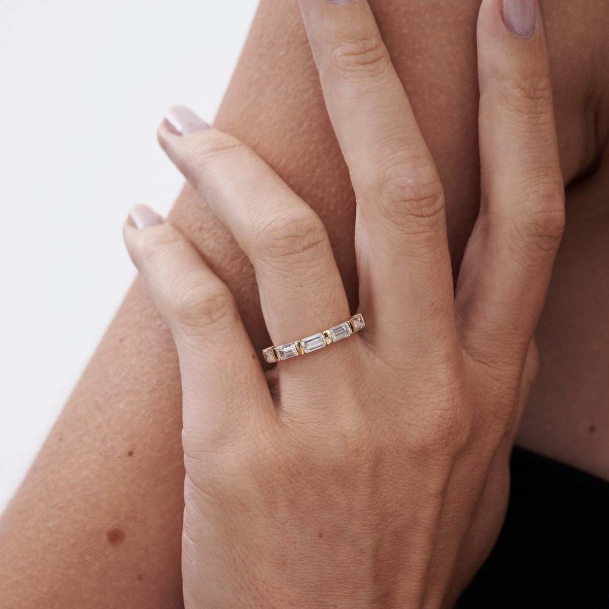 Celine is created with five emerald-cut lab-grown diamonds. The approximate total carat weight of this piece is 1.75ct. An elegant half-infinity row of five emerald cut lab-grown diamonds — secured seamlessly by solid gold bar settings.