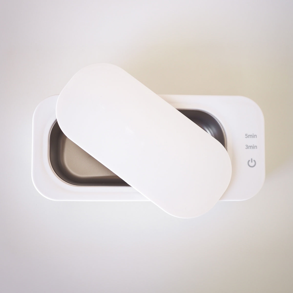 White electronic device with a power button on a light background