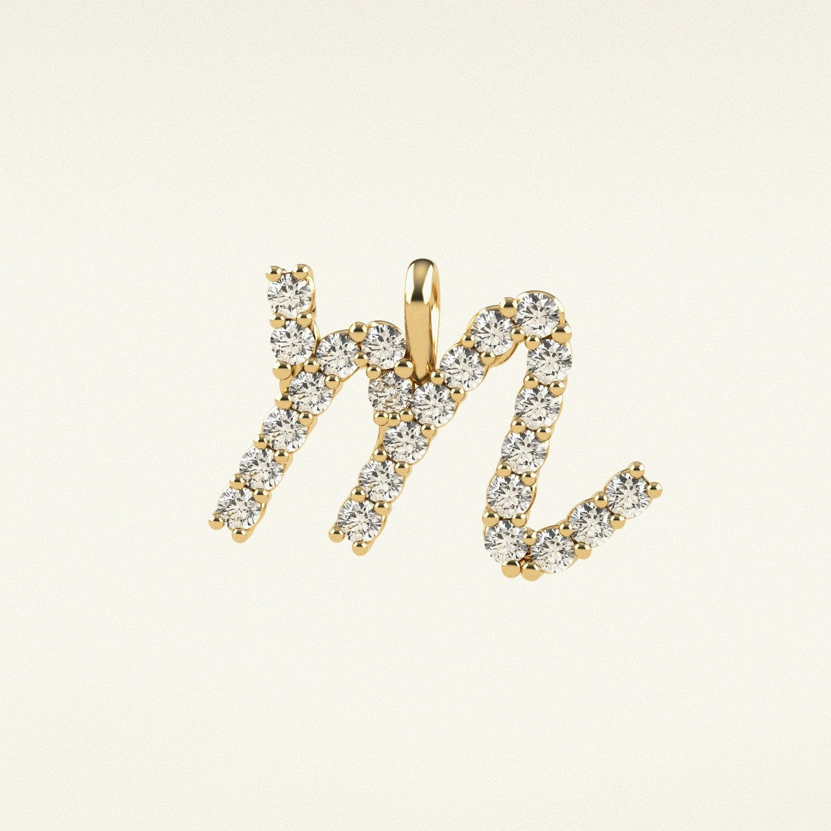 Gold and diamond letter 'M' pendant on a beige background