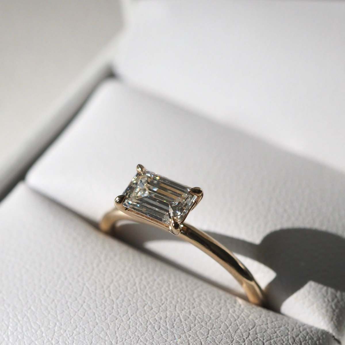A modern take on the traditional solitaire engagement ring — featuring a beautiful east-west set emerald cut lab-grown diamond held within a simple four-talon claw setting.