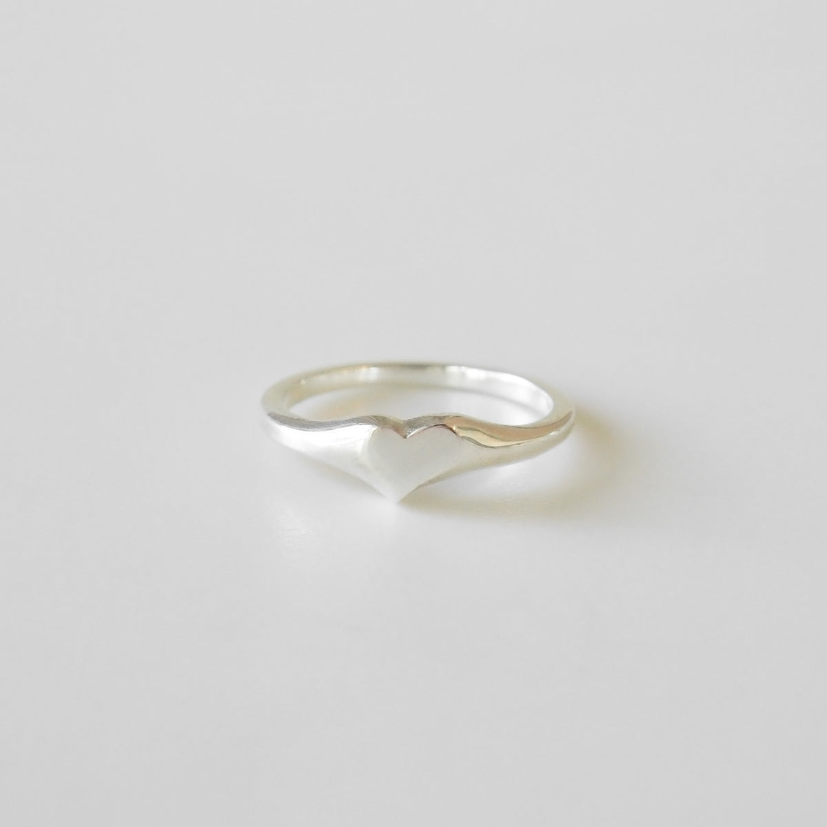 Silver ring with wavy design on a light gray background