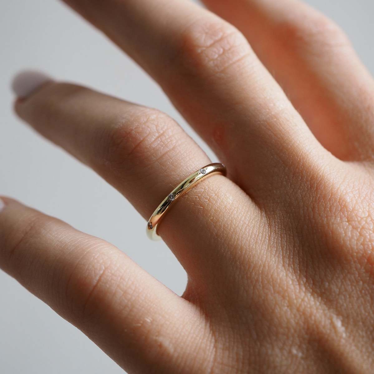 A solid gold round profile band for the modern minimalist — set with eight ornately set lab-grown diamonds spaced along the top or side edge. 