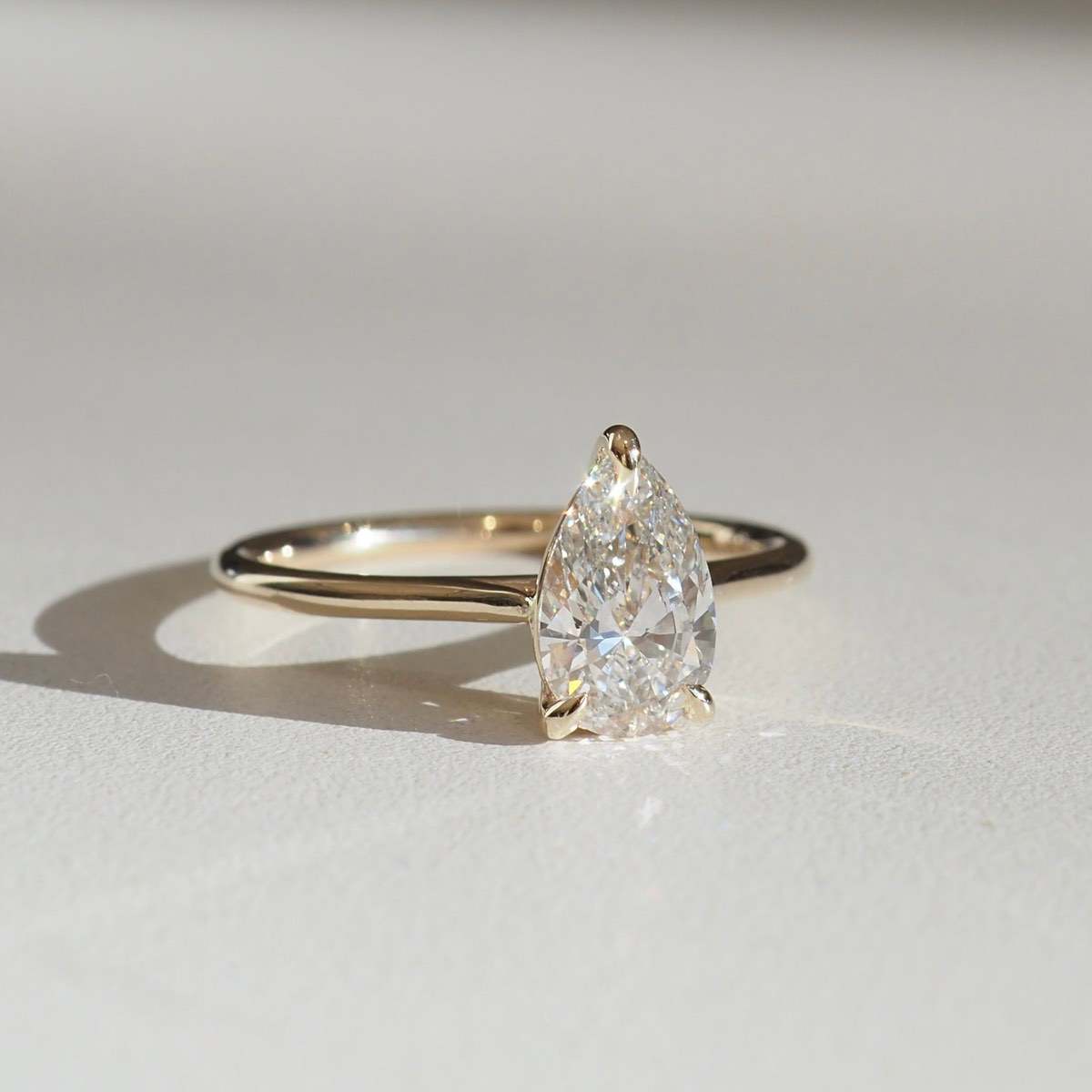 A feminine three claw solitaire engagement ring — featuring a pear cut lab-grown diamond held atop our signature sweep style band. 