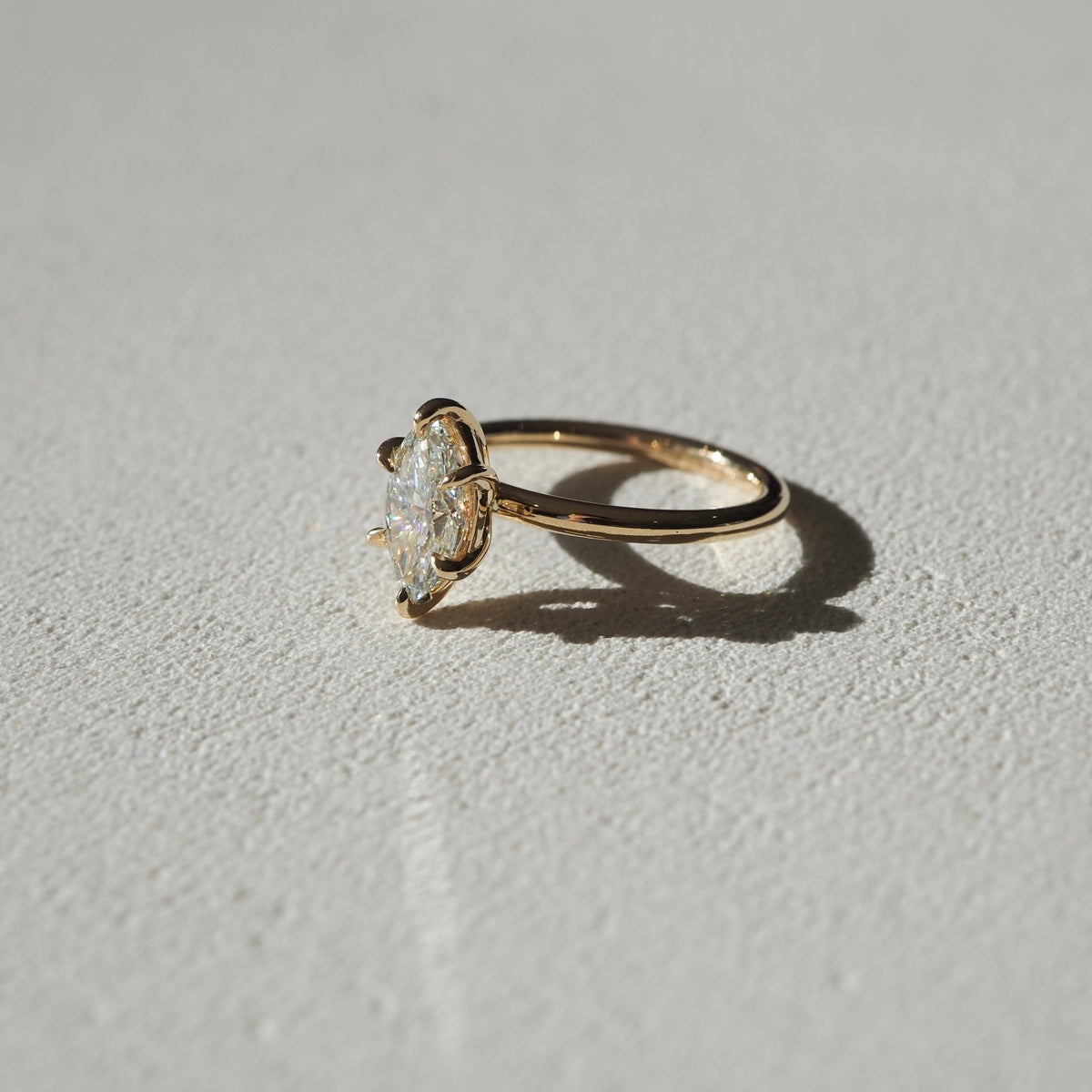 A mesmerising six claw solitaire engagement ring — showcasing the slender silhouette of a marquise cut lab-grown diamond - set in solid 18ct yellow gold. 