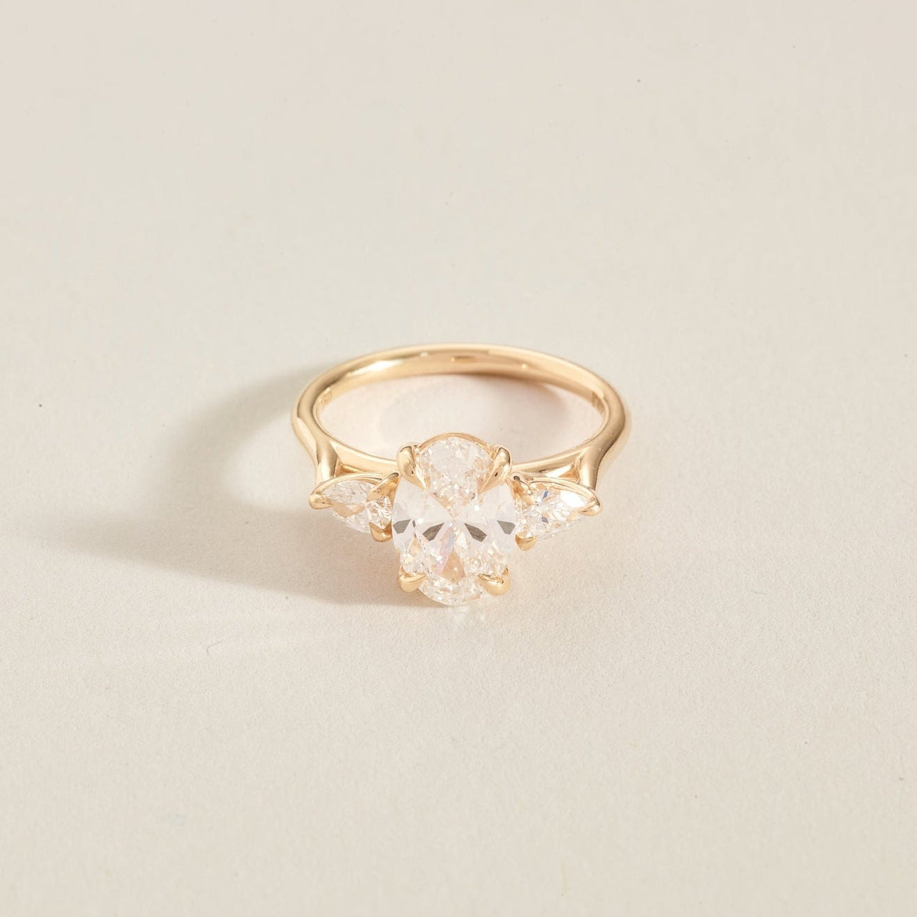 Gold ring with clear gemstones on a light beige background