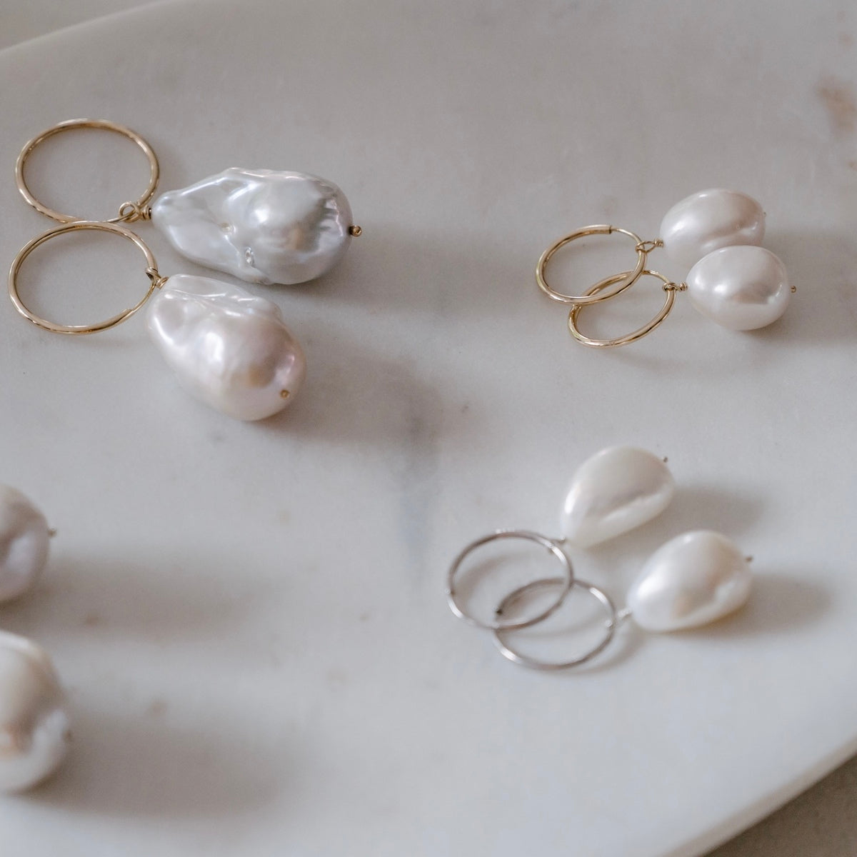 An array of our hand-wrapped solid gold and silver baroque pearl earring on 15mm and 20mm everyday sleepers.