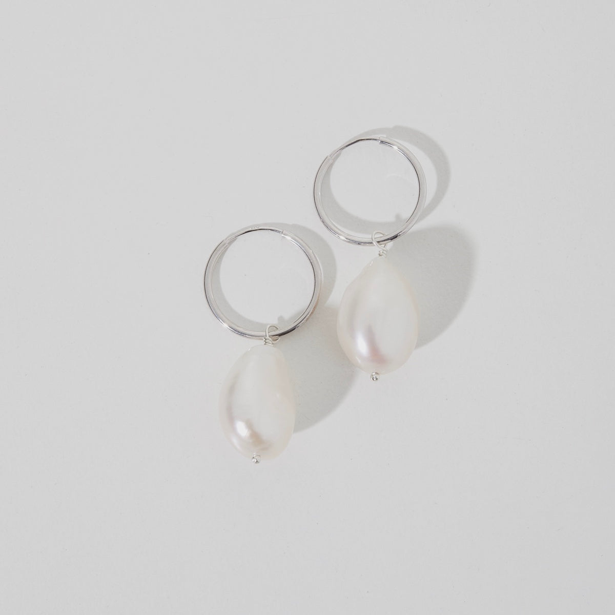 Flat lay of our solid small baroque pearl earrings in sterling silver on 15mm everyday sleepers.