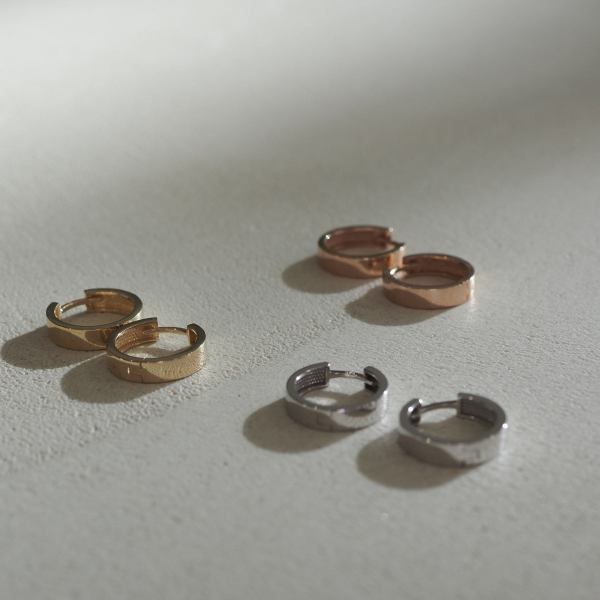 Solid Yellow Gold, Rose Gold, and White Gold Huggies: flat lay of Small hoop earrings made for everyday wear