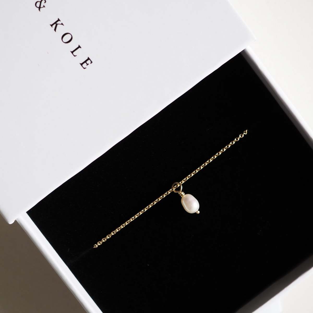A Solid Yellow Gold Hand Wrapped Baroque Pearl Necklace wrapped up in a white K&K jewellery box