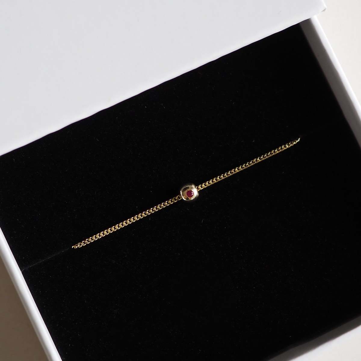 Our Solid 9ct Yellow Gold Tiny Birthstone Charm Bracelet with a personalised Ruby stone wrapped up in a Kate & Kole jewellery box
