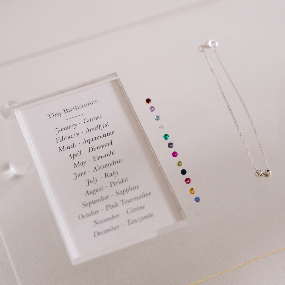 A flat lay of our 12 Tiny Birthstones to choose from for our Tiny Birthstone Charm Necklace