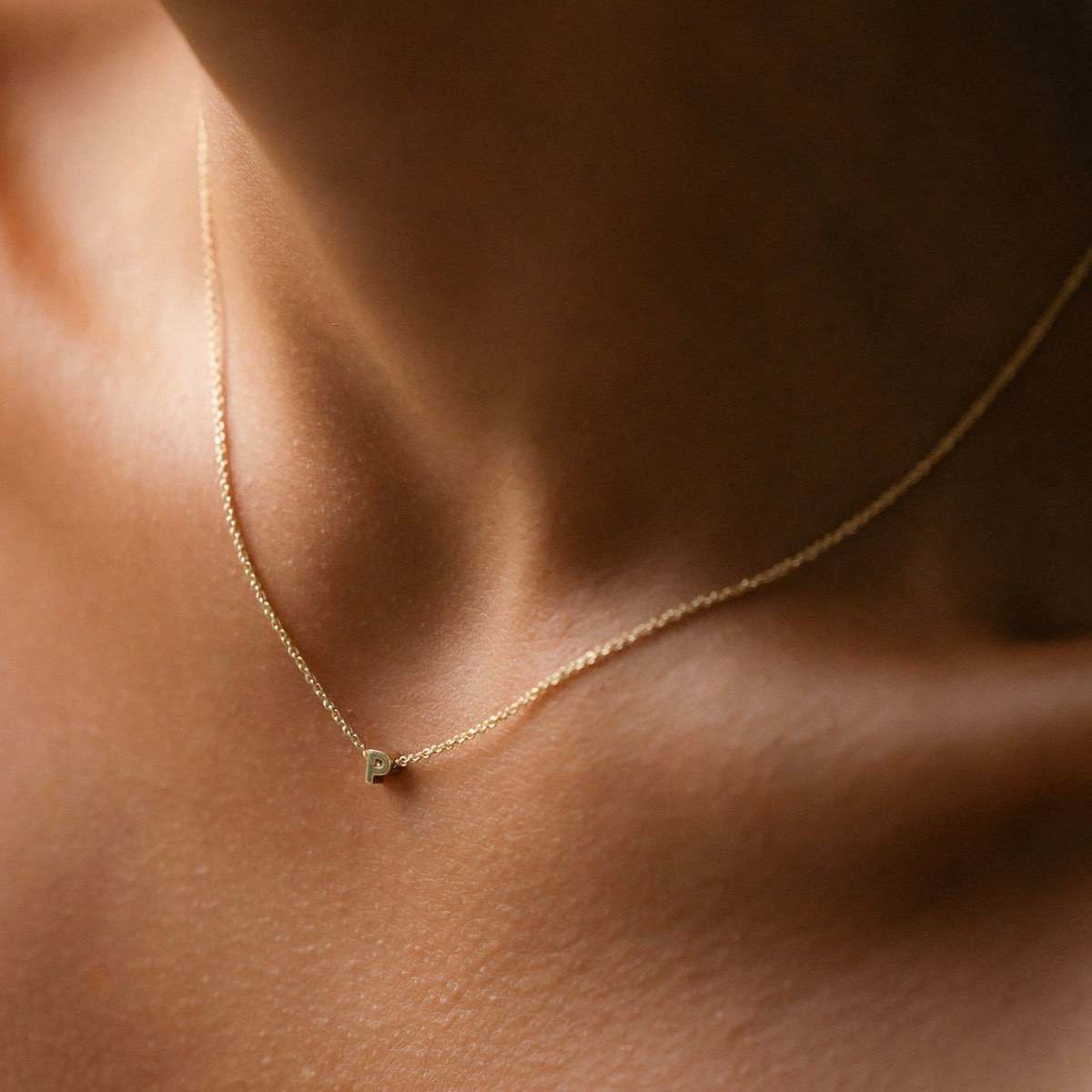 Hand finished solid gold letter necklace: Close up of a model wearing our beautiful 9ct yellow gold Tiny Letter P Charm Necklace with a 40cm cable chain
