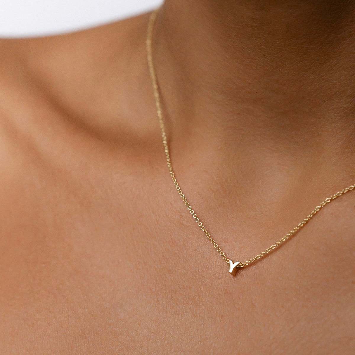 Hand finished solid gold letter necklace: Close up of a model wearing our beautiful 9ct yellow gold Tiny Letter Y Charm Necklace with a 40cm cable chain
