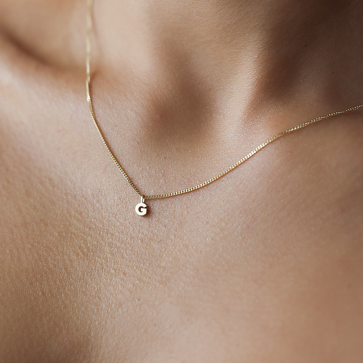 Our newest addition to our 'Tiny' collection. Our 9ct yellow gold tiny letter dangle necklace is shown on a 45cm diamond curb chain. 