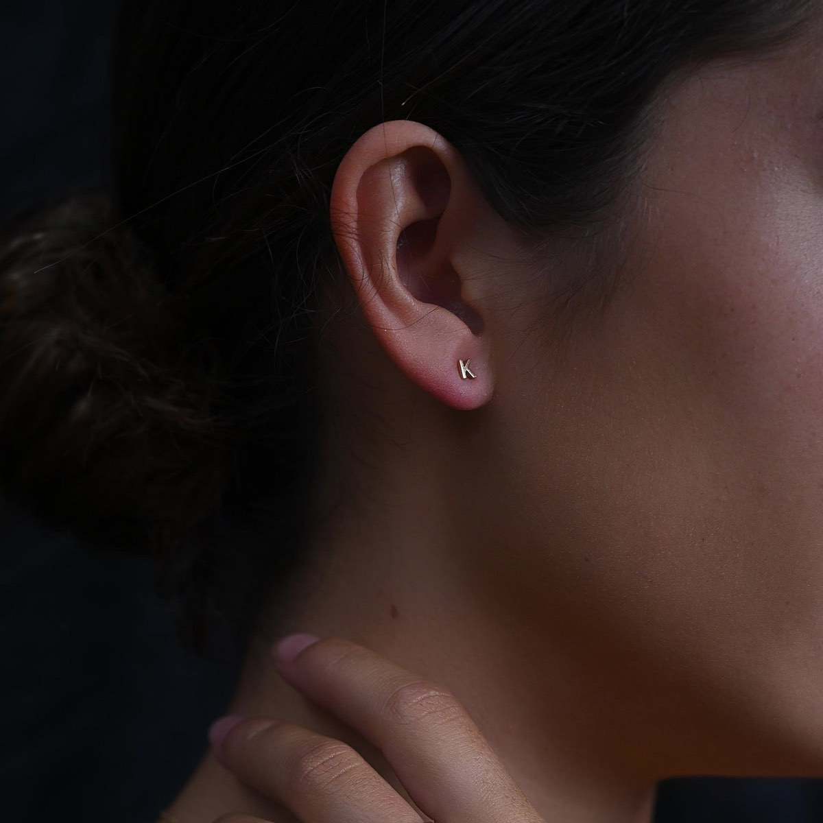 Model wearing Tiny Letter Studs in Letter K in 9ct yellow gold