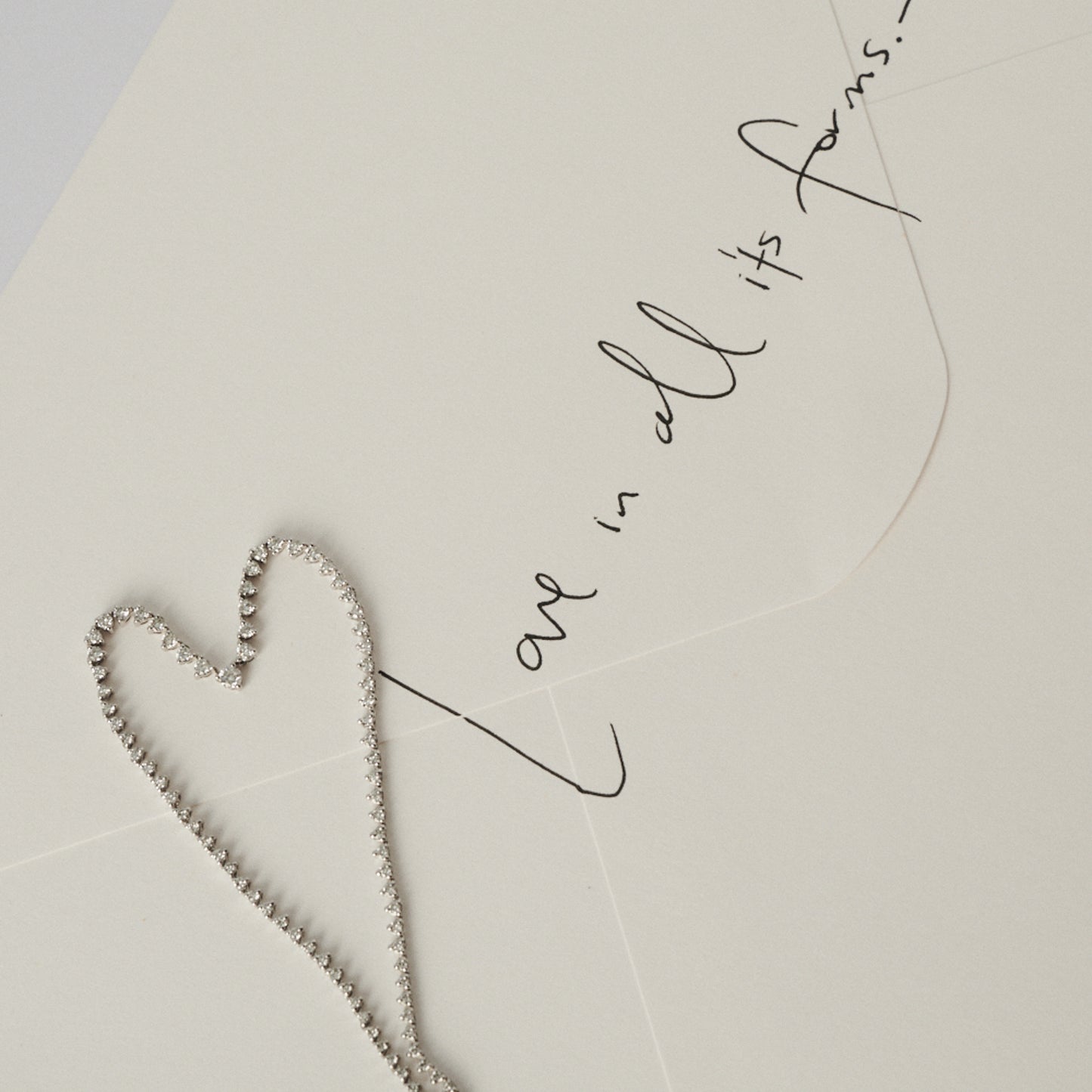 Heart-shaped necklace on a light background with cursive text