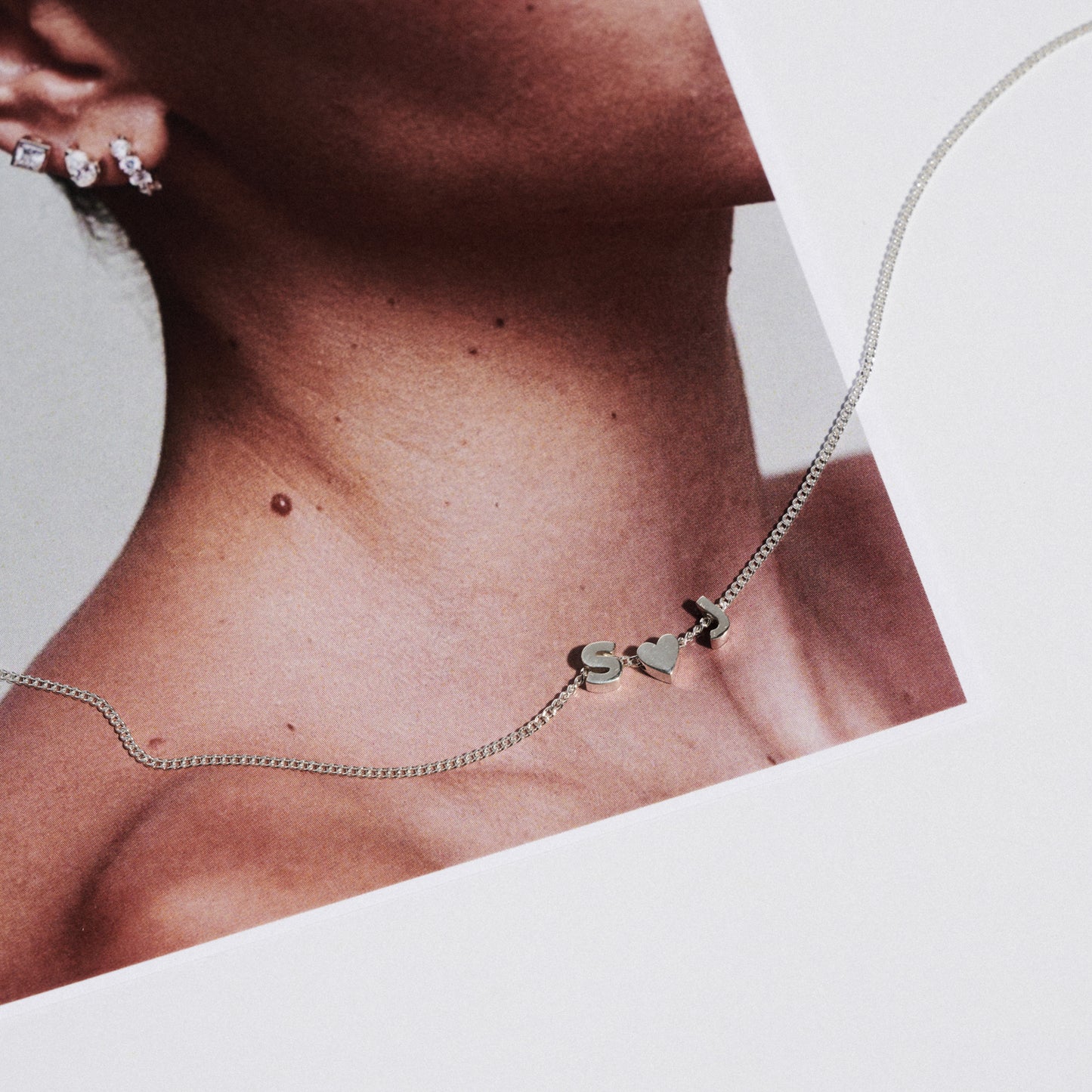 Close-up of a silver necklace with heart-shaped pendants on a neutral background